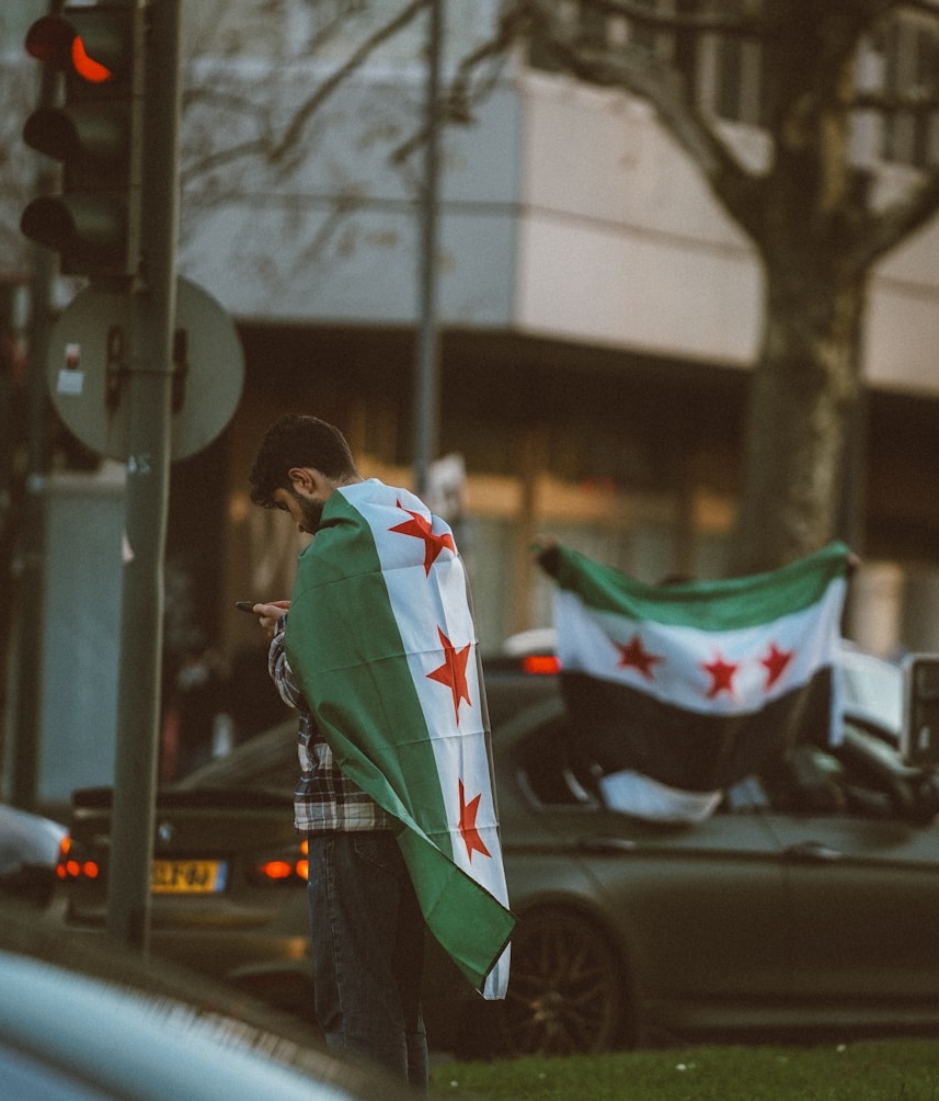 رجل يرتدي العلم السوري كعباءة.