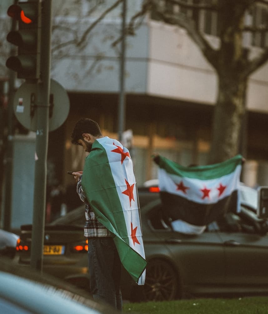 رجل يرتدي العلم السوري كعباءة.